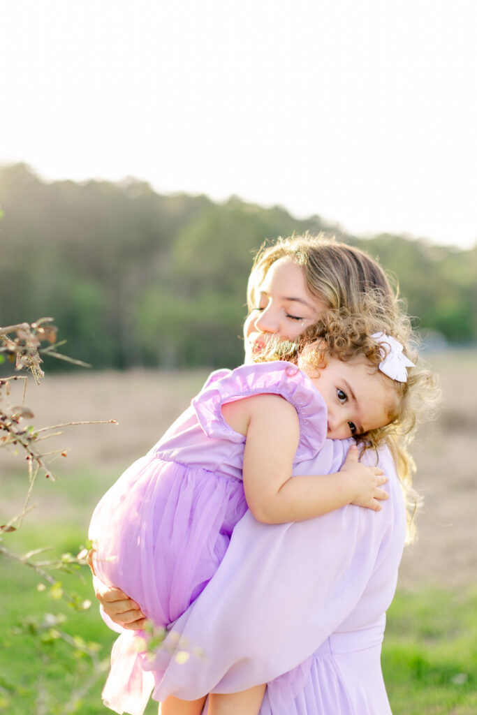 Mommy hugs daughter in golden light in East End Park, Texas