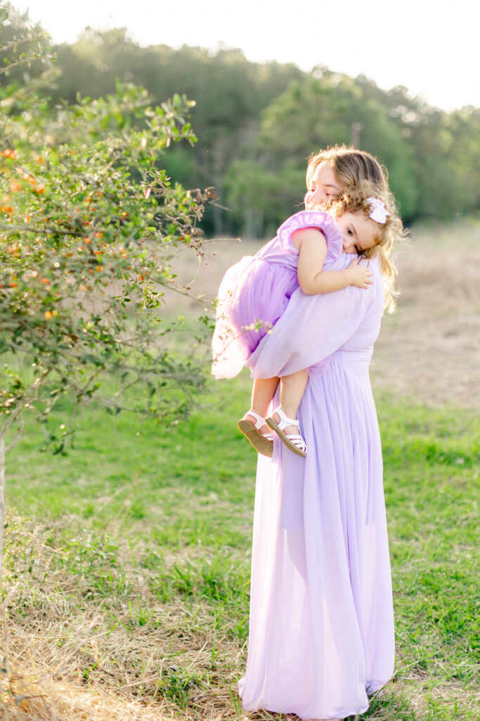 Mommy hugs daughter in an open field for photo session