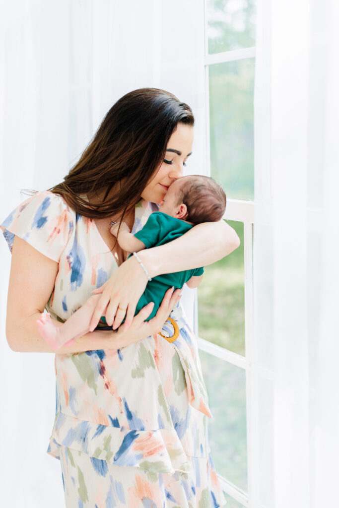 mother kisses baby at the oak atelier the willow glass house in conroe texas