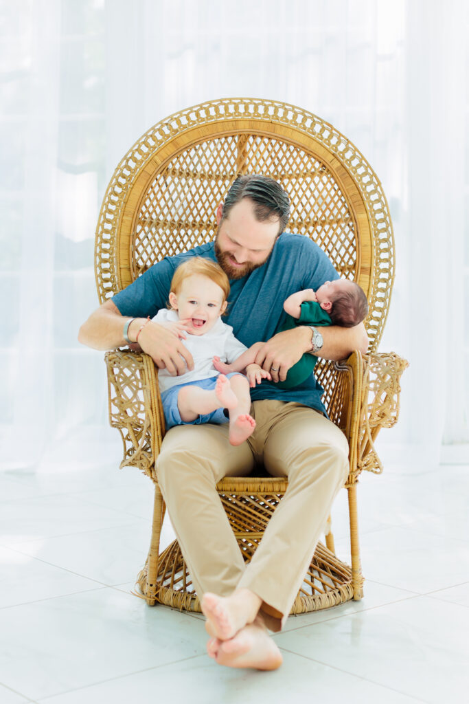 father and two sons in wicker chair at photo session in conroe, texas