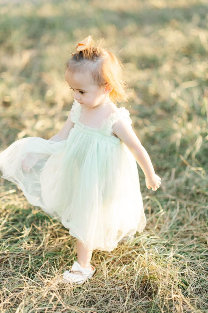 girl in green tulle dress walks through open field for houston fall mini photo shoot