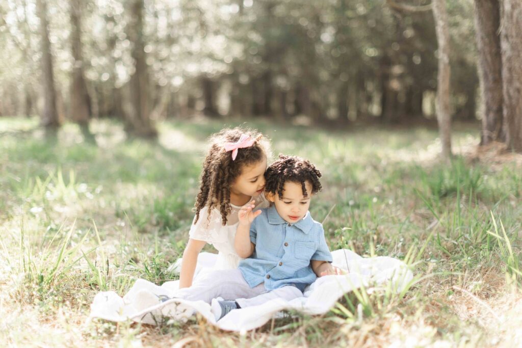 siblings play together on a blanket in kingwood field for allie nichols photography for Spring Family Photos