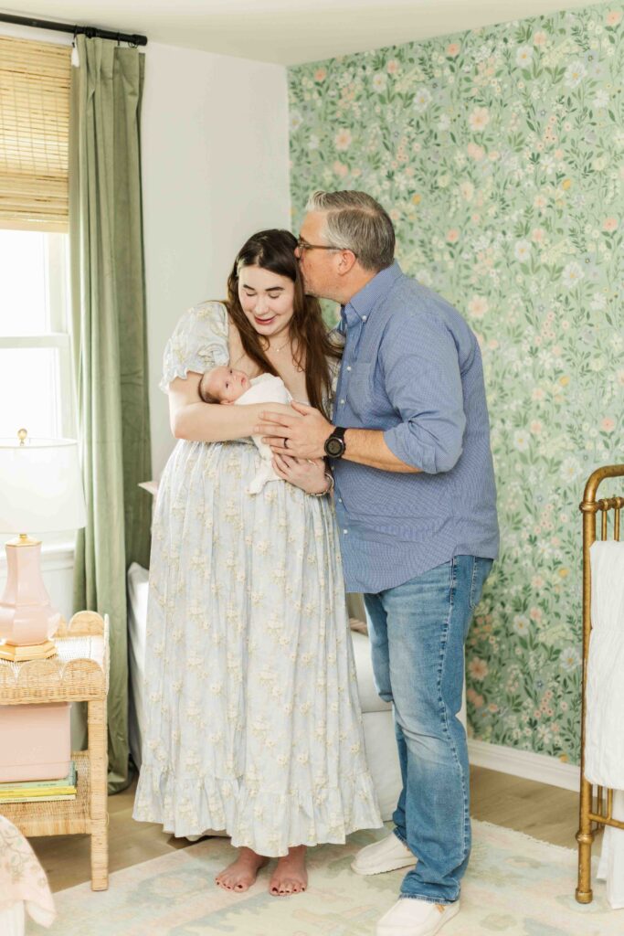 mom and dad stand together in baby's nursery for houston in-home photo session