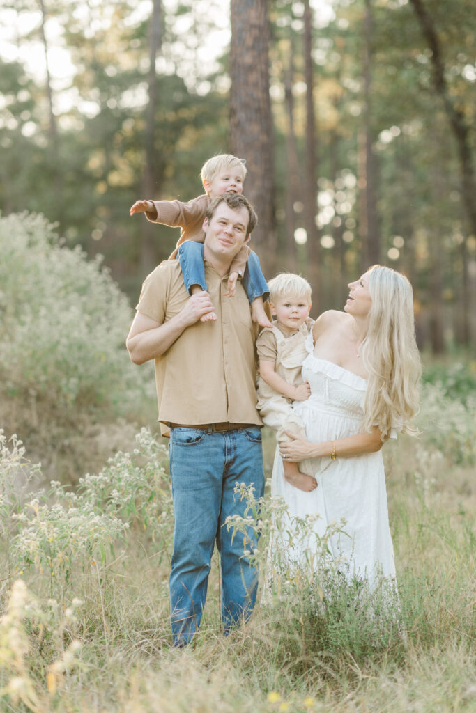 family wearing light colors plays together in a field for a fall houston maternity session