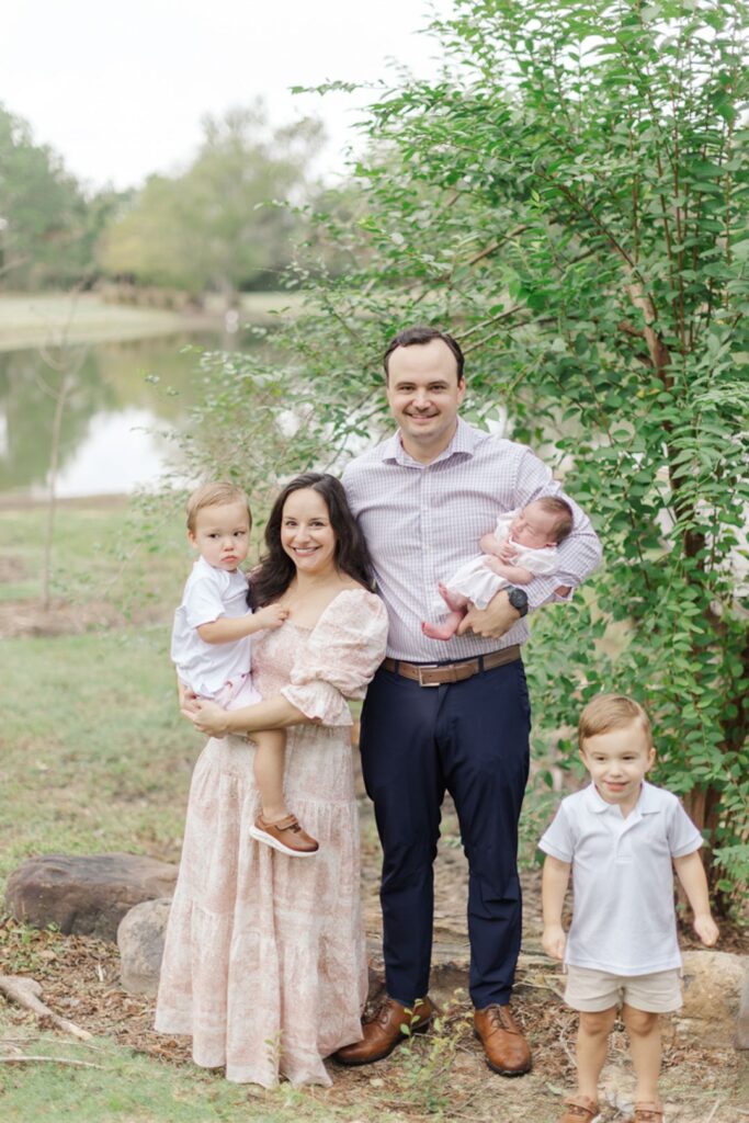 family smiles together in front of a houston pond wearing boutique outfits