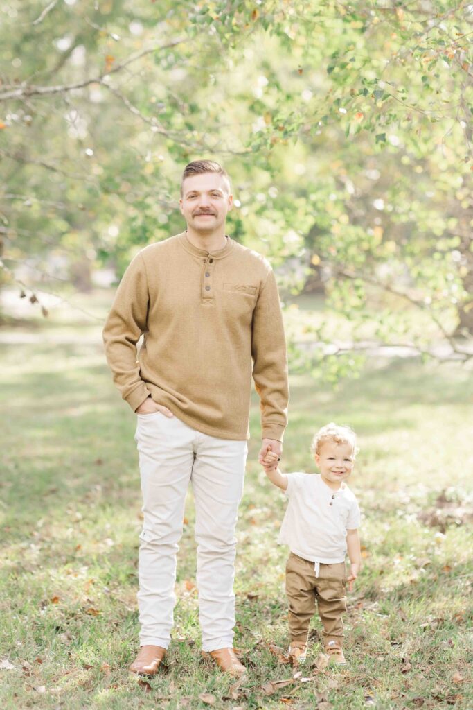 dad holds his son's hand for family photos in boutique outfits